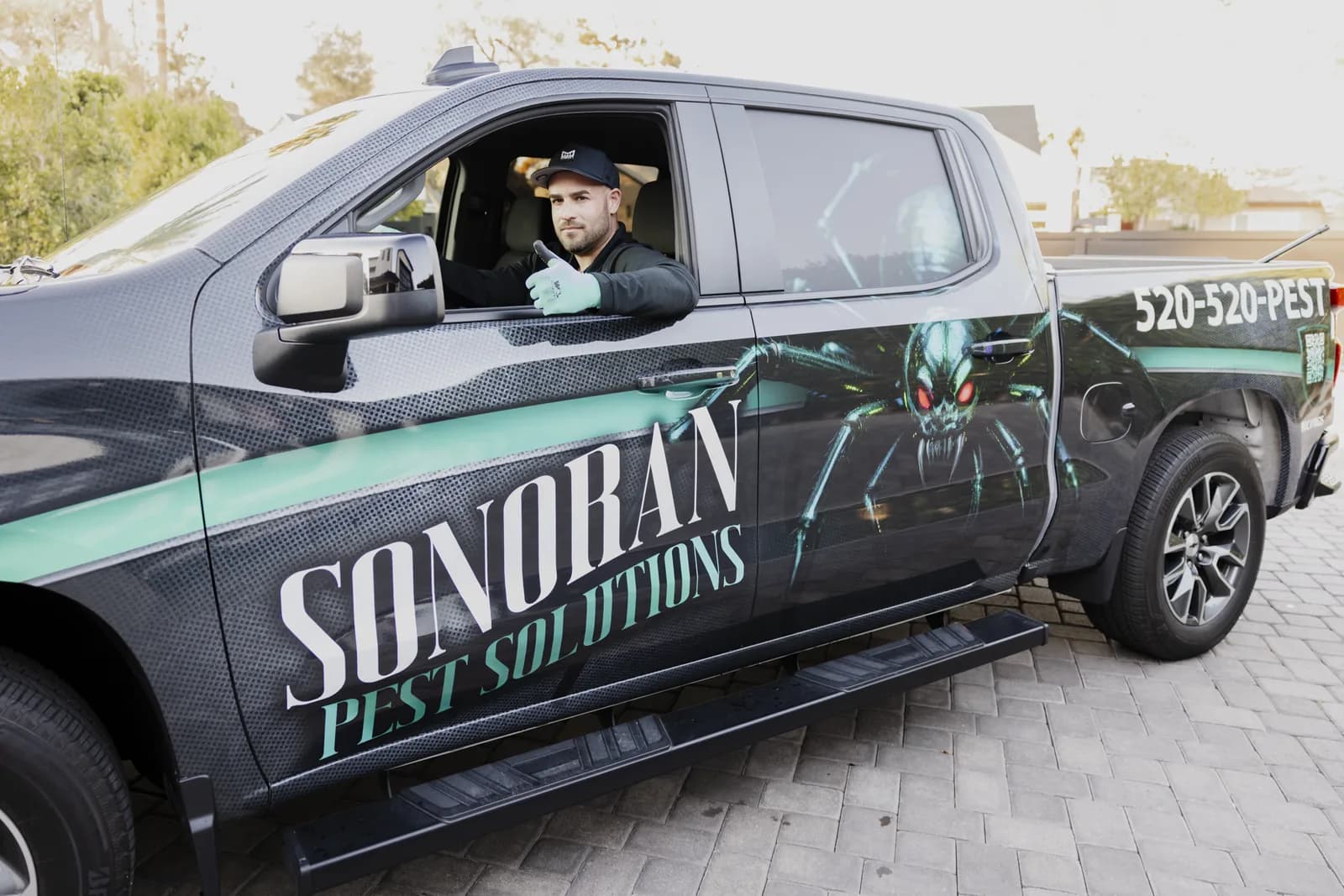 Owner giving a thumbs up from the Sonoran Pest Solutions wrapped service truck